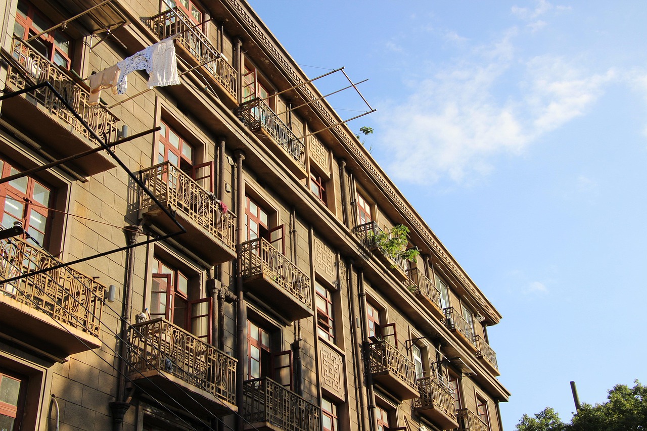 在广州市核心城区越秀区，一个名为“黉桥·小石集”的微改造项目在短短半年内，将17栋上世纪中后期的危旧老房蝶变为现代宜居的综合楼，不仅显著提升了居民生活品质，也为中国城市更新探索出一条政府不投入巨资、多方共建的新路径。

老旧危房的华丽转身

“黉桥·小石集”项目位于广州市越秀区洪桥街道，其前身是建于上世纪60至80年代的17栋老旧房屋。这些房屋多为C、D级危房，户均面积仅十几平方米，采光条件极差，巷道最窄处不足2.5米，消防和急救车辆难以通行，每逢台风季节，居民们都生活在担忧之中。面对居民改造意愿强烈、城市治理面临挑战的局面，越秀区政府决定启动这一微改造项目。

项目于2025年4月正式动工，至同年10月完工，历时仅半年。改造后的“黉桥·小石集”是一栋四层高的红砖灰瓦建筑，风格现代简约。一层规划为便利商铺，二至四层则为配有独立卫浴、明亮整洁的公寓。此外，项目还设计了健身房、养老服务站和托育点等公共空间，受到了年轻群体的青睐，实现了从“忧居”到“优居”的显著转变。

创新筹资与协商机制破解改造难题

老旧房屋改造面临的最大挑战之一是资金筹措、居民诉求差异以及复杂的房屋产权问题。“黉桥·小石集”项目通过一系列创新模式有效解决了这些难题。

多元化筹资模式减轻财政压力

越秀区采用了“居民出一点、企业投一点、政府补一点”的多元化筹资模式，避免了财政巨额投入。具体而言，私房居民每平方米出资4400元人民币（约合600美元，按当前汇率估算）；公房部分则由国有企业北秀公司投入约1900万元人民币（约合260万美元），改造后北秀公司将以“租商融合”的业态运营，预计每月可产生13.7万元人民币（约合1.9万美元）的收入。这种模式有效撬动了社会资本参与，实现了政策引导、企业参与和群众共建的良性互动。

“一户一议”协商机制凝聚共识

为充分协调各方利益，洪桥街道于2023年7月成立了工作专班，牵头组织业主代表、周边居民代表和项目设计团队等进行反复研究协商。专班成员“一户一户走、一家一家谈”，耐心解读新模式下的相关政策，充分听取居民意见和建议。即使面对最终决定不参加改造的两户居民，街道也展现出包容度，并对他们的住所进行了微改造，最终取得了最大程度的共识，确保了项目的顺利推进。

产权整合与政策支持加速改造进程

针对不同权属房屋的改造难题，项目创新性地采用了“统一设计、归集产权、整体报批”模式，由国有企业北秀公司作为实施主体统筹推进。此外，广州市于2024年6月出台了新的城市更新规定，其中“地上建筑规模增量原则上不超过30%”等政策为危旧房的“小连片”自主改造提供了政策红利和“松绑”，极大地提升了企业和群众参与改造的积极性。

先进建造技术与优化设计提升品质

在项目施工期间，设计团队和规划专家充分考虑了城区中心施工扰民、消防通道不足和采光差等实际问题，通过引入先进技术和优化设计方案，有效提升了改造效率和居住品质。

模块化建造技术缩短工期

“黉桥·小石集”项目采用了BMC钢结构模块化建造技术，通过将56个建筑模块在工厂预制，再运至现场进行组装，使得工期缩短了约60%。这种高效的建造方式不仅减少了对周边居民的影响，也加快了项目交付速度。

创新设计方案解决核心痛点

针对消防通道不足的问题，专家团队提出了“6米骑楼退让”方案，有效拓宽了消防通道。同时，为解决老旧房屋普遍存在的采光差问题，设计团队通过整合空间形成了中庭，并增设了采光井，显著改善了室内光照条件。政府在这一过程中充分尊重专业人员的意见，有力推动了这些创新方案的落地实施。

中国城市发展逻辑的深层变革

“黉桥·小石集”的成功案例，折射出中国城市治理正在经历一场深层变革。过去十年，中国城市发展以大规模增量扩张为主要特征，推土机和塔吊是城市建设的“标配”。然而，随着城市化进程进入新阶段，大规模增量扩张的时代已成为过去，城市发展逻辑正经历根本性转变，从“土地财政”模式转向“存量提质增效”，从“做大增量”走向“做优存量”、从“外延扩张”迈向“内涵提升”。

在这一转型过程中，政府的角色也发生了深刻变化。在“黉桥·小石集”项目中，政府不再是建设的“包办者”或“土地经营者”，而是转变为“平台搭建者、规则制定者、利益协调者、建设赋能者”。通过健全协商沟通机制，政府在复杂的利益格局中凝聚共识；通过灵活调整政策，将思路变为行动；通过从局部改起，逐步推进老城焕新。越秀区的实践表明，精细化“绣花针”式的微改造，正成为中国城市更新的重要方向，推动着城市治理模式的现代化和可持续发展。


参考来源

新华社经济随笔·四中全会精神在基层丨财政不花大钱，政府靠什么让“忧居”变“优居”？ — 新华社新闻（2025-10-31）：查看原文